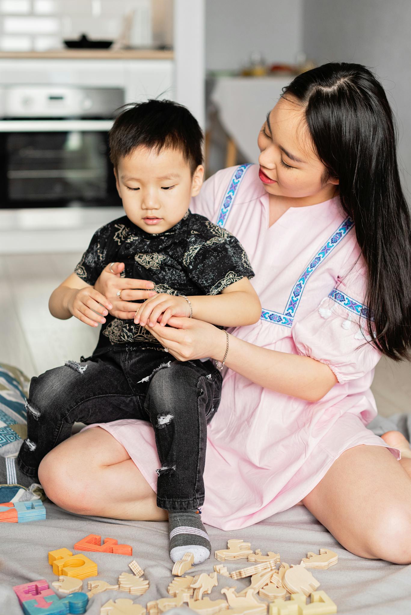A joyful mother and son bonding over wooden toys in their home.