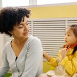 Child plays pretend doctor with stethoscope and adult, fostering imagination indoors.